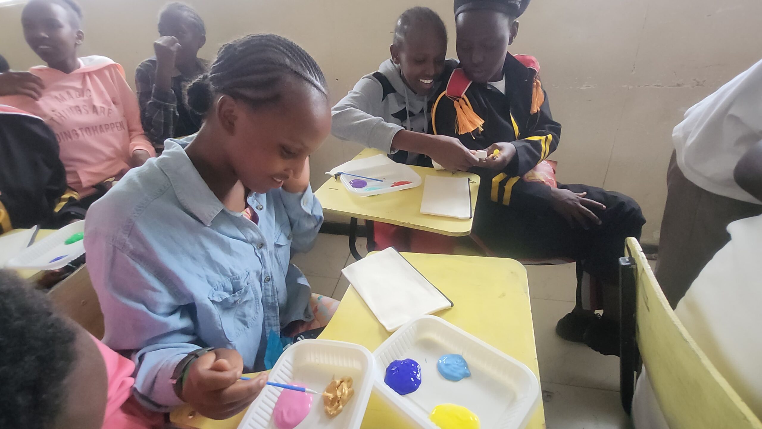 Children in class painting on small hand bag