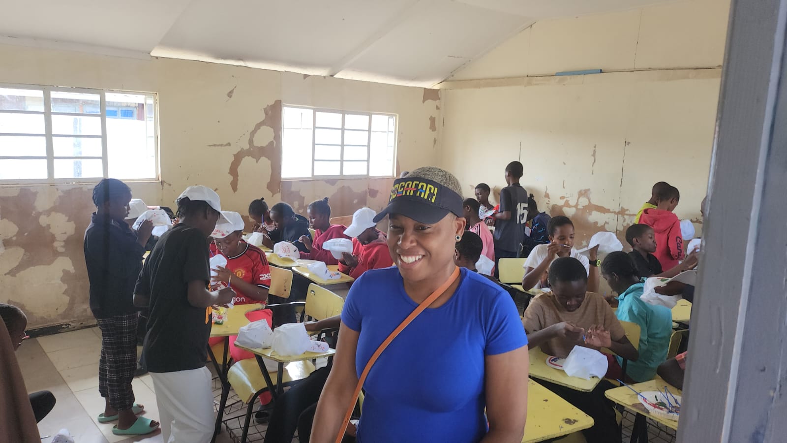 A donor standing in class with students making some paintings on white hats