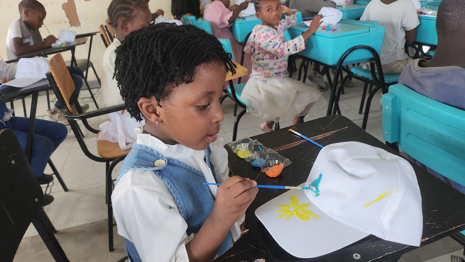 Children in class making some paintings on white hats